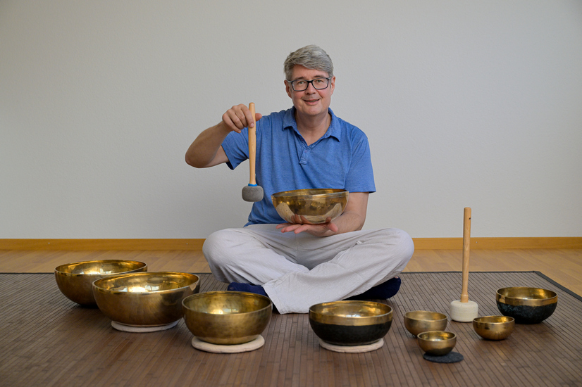 Charly Locher, Inhaber von Mitklang, spielt eine Klangschale an.